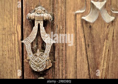 Vieux heurtoir de porte ornemental gravé en bronze classique dans une maison méditerranéenne Banque D'Images