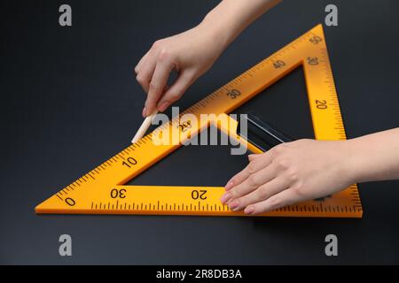 Femme dessin avec craie et règle triangulaire sur tableau noir, gros plan Banque D'Images