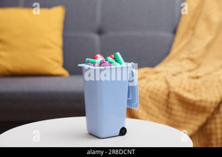 Mini-bac de recyclage avec différents types de piles sur table blanche à l'intérieur Banque D'Images