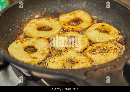 Les pommes en tranches sont frites dans une poêle à gaz. Banque D'Images