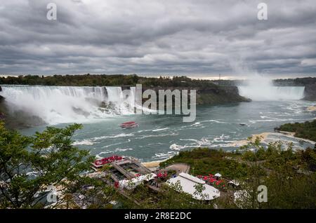Vue panoramique sur les chutes du Niagara. Bateaux avec des touristes portant des manteaux de pluie roses qui naviguent sur la rivière. Ontario. Canada. Banque D'Images