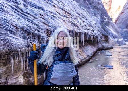 États-Unis, Utah, Springdale, parc national de Zion, femme âgée traversant la rivière en randonnée dans les montagnes Banque D'Images