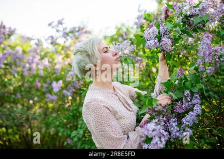 Portrait de femme sentant les fleurs de lilas dans le jardin Banque D'Images