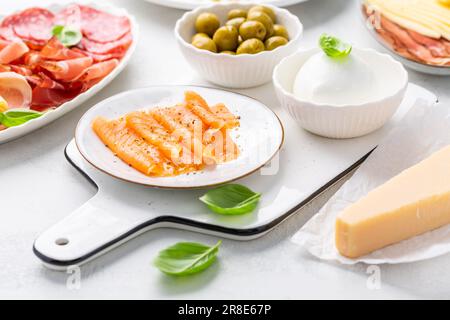Hors-d'œuvre avec différents antipasti, charcuterie, en-cas, assiette de viande avec fromage et olives épicées, carpaccio de saumon et salade de tomates Banque D'Images