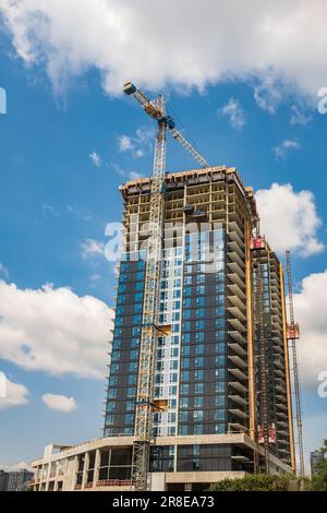 Chantier de construction avec grues nouveau développement dans la ville. Immeuble résidentiel en béton de grande hauteur en construction contre le ciel bleu. CopySpace pour le texte Banque D'Images