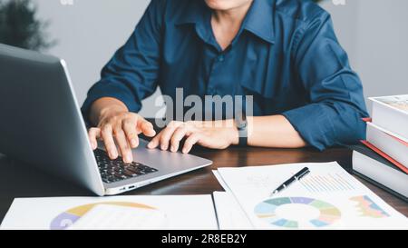 Une jeune femme de garde bancaire utilisant une calculatrice, un ordinateur portable, une feuille de travail papier pour analyser les informations de données. Elle est une financière professionnelle de ba Banque D'Images