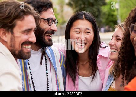 Groupe multiculturel d'amis se regardant les uns les autres souriant tout en embrassant dans le cercle dehors. Banque D'Images