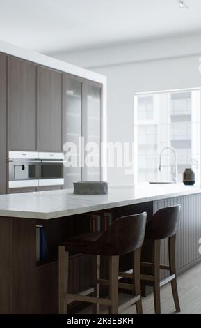 Minimalisme de la cuisine. Cuisine en bois avec grande île longue et tabourets de bar. Banque D'Images