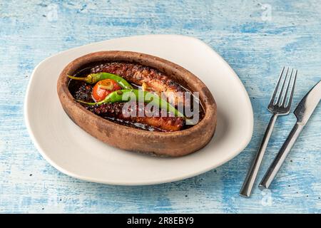 Cocotte de poulpe avec tomates et poivrons sur fond de pierre bleue Banque D'Images