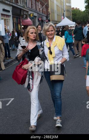 Les femmes amies marchent le long du centre de la route, les bras autour de l'autre. Ils sont à la mode et décontractés habillés, on porte son iphone. La route des rois est en partie fermée à la circulation, pendant le Platinum Jubilee Street Party, qui soutient l'appel de crise de la Croix-Rouge britannique en Ukraine. Chelsea, Londres, Angleterre 4 juin 2022. ANNÉES 2020 ROYAUME-UNI HOMER SYKES Banque D'Images