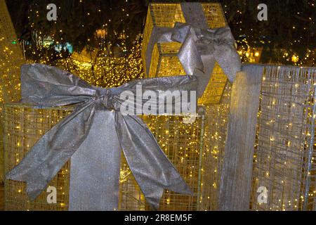 Des cadeaux exceptionnels sous l'arbre de Noël de la ville dans les guirlandes illuminées de nuit Banque D'Images