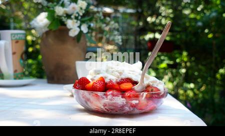 Fraises fraîches juteuses avec crème sur une table de jardin. Une tasse de cappuccino. Banque D'Images