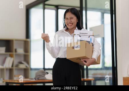 Concept de démission. Employé tenant une boîte de biens dans un bureau après la démission, moment heureux Banque D'Images