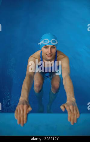 Vue de dessus sur le jeune sportif course arrière dans la piscine intérieure Banque D'Images