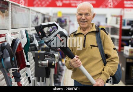 Sénior homme retraité achetant l'aspirateur vertical dans la salle d'exposition du magasin d'appareils électriques Banque D'Images