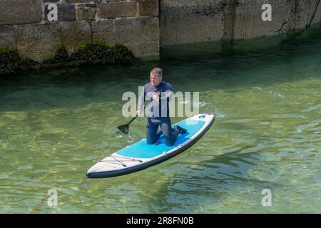 18 juin 2023. Cullen, Moray, Écosse. C'est un homme paddleboard dans le port de Cullen lors d'une journée d'été très ensoleillée. Banque D'Images