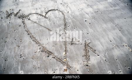 Le coeur du Loveheart dessiné dans le sable sur une plage. Banque D'Images