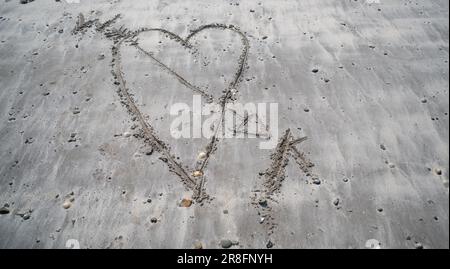 Le coeur du Loveheart dessiné dans le sable sur une plage. Banque D'Images