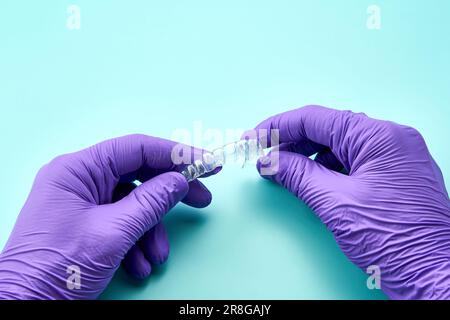 Technicien dentaire avec un corset invisible dans un laboratoire dentaire, portant des gants violets et une table verte. Banque D'Images