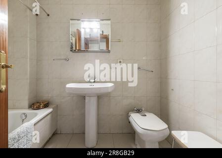 Salle de bains classique et obsolète avec toilettes et un petit meuble en métal et miroirs Banque D'Images