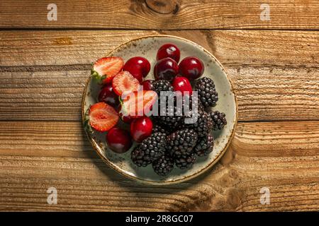 un petit plat aux baies mûres, aux fraises et aux cerises sans tiges Banque D'Images