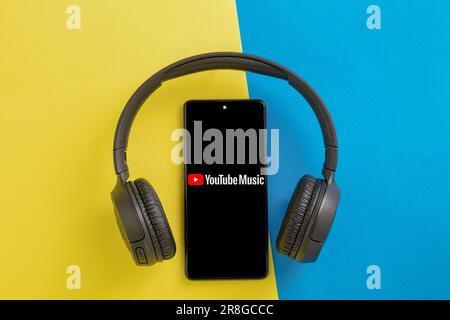 Pologne, Varsovie - 21 juin 2023 : application YouTube Music phone. Lecteur vidéo sur l'écran du téléphone portable et casque sans fil sur fond sombre Banque D'Images