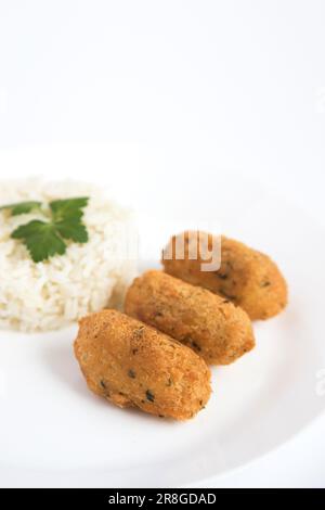 Boulettes de morue, ou « bolinhos de bacallahau », très célèbre dans la gastronomie portugaise. Assiette de pâtisseries à la morue servies avec du riz blanc. Banque D'Images