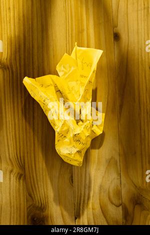 Feuille de papier jaune froissé sur fond de bois , note manuscrite Banque D'Images