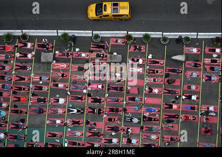 New York, États-Unis. 21st juin 2023. Un taxi jaune de la ville de New York passe devant les amateurs de yoga participant au solstice d'été annuel de yoga à Times Square, New York, NY, 21 juin 2023. Le solstice marque le premier jour de l'été et est le jour le plus long et la nuit la plus courte de l'année. (Photo par Anthony Behar/Sipa USA) crédit: SIPA USA/Alay Live News Banque D'Images