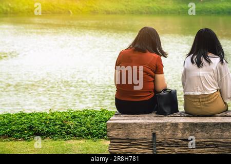Vue arrière des femmes asiatiques se détendant et se détendant au bord de la rivière. Détendez-vous en toute liberté pendant les vacances d'été. Bonne famille à l'extérieur Banque D'Images