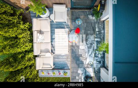 Vue de dessus du propriétaire caucasien de maison laver la passerelle à sa petite terrasse arrière-cour avec l'outil de nettoyage de surface de puissance. Banque D'Images