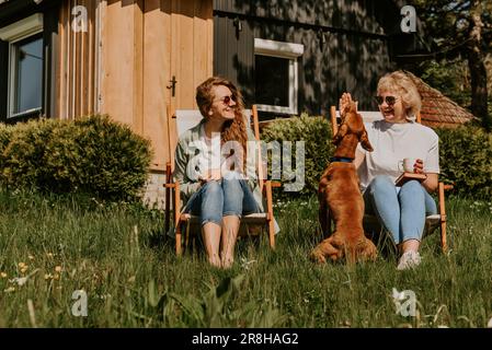 Mère et fille adulte jouant avec chien à l'extérieur Banque D'Images