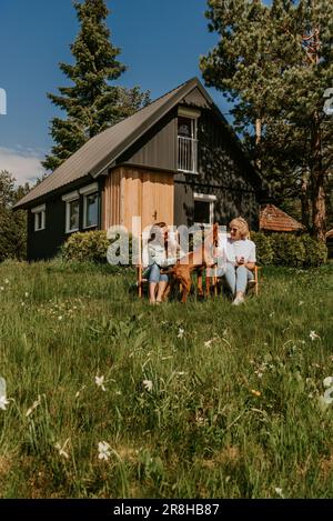 Mère et fille adulte avec chien se prélassant à l'extérieur Banque D'Images