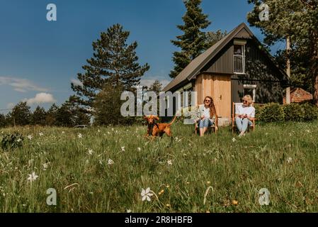 Mère et fille adulte avec chien se détendant à la campagne Banque D'Images