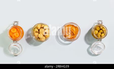 Légumes fermentés et champignons dans des bocaux en verre sur fond bleu Banque D'Images