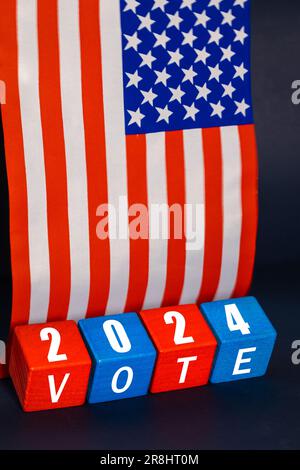 USA Election 2024, vote de l'élection présidentielle américaine, concept, blocs de bois dans les couleurs nationales américaines, l'année et le texte vote, le fond du drapeau américain, vertic Banque D'Images
