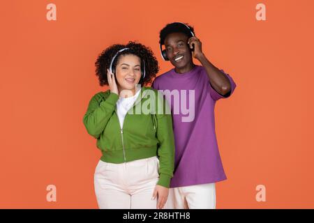Joyeux couple multiethnique joyeux, à l'écoute de la musique et souriant Banque D'Images