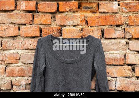 la veste grise pour femmes est accrochée à des cintres sur un vieux mur de briques d'une maison dans la rue, mode pour femmes Banque D'Images