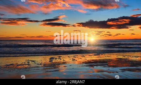 Lever de soleil au-dessus de la mer du Nord au large de la plage de Brora dans les Highlands avec des reflets de l'aube dans le sable humide Banque D'Images