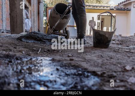 Un travailleur de la construction prépare du ciment sur un chantier de construction. Gros plan d'une personne méconnaissable au niveau du sol. Banque D'Images