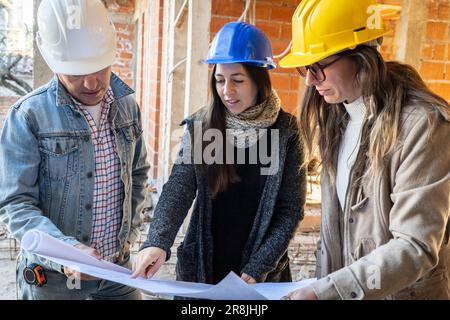 Un ingénieur latin et une équipe d'architectes féminins avec un projet de construction en cours. Directeur de construction et ingénieur travaillant sur un chantier de construction Banque D'Images