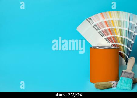 Boîte de peinture orange, échantillons de palette de couleurs et pinceaux sur fond turquoise. Espace pour le texte Banque D'Images