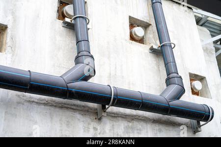 Les tuyaux en polyéthylène drainent l'eau des rails du SKY train. Drainage de pipeline en HDPE. Un tube en PE noir a été installé sur un mur de bâtiment. Tuyau en polyéthylène Banque D'Images