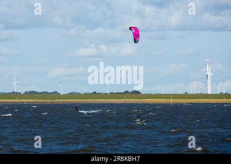 Un kite surfeur passe les vagues près du port de Dagebüll. Le district de Dagebüll Hafen (port de Dagebüll) est situé directement sur les rives de la mer des Wadden. Le port assure des liaisons régulières en ferry vers les charmantes îles de Foehr et d'Amrum. Banque D'Images