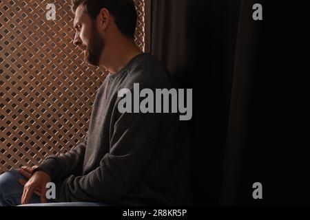 Énervé homme à l'écoute du prêtre pendant la confession dans le stand Banque D'Images