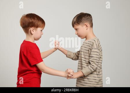 Deux garçons se battent sur fond gris clair. Intimidation des enfants Banque D'Images