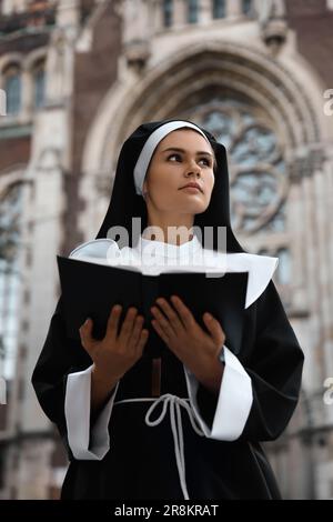 Jeune nonne lisant la Bible près de la cathédrale en plein air Banque D'Images
