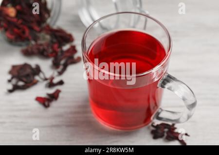 Délicieux thé hibiscus et fleurs sèches sur table en bois blanc, en gros plan Banque D'Images