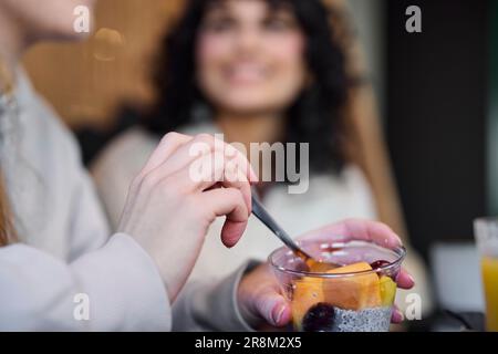 Femme mangeant un dessert de fruits au café Banque D'Images