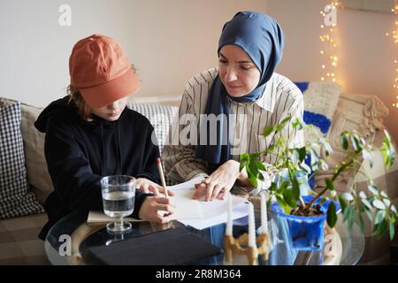 Mère portant le hijab aidant son à faire ses devoirs Banque D'Images